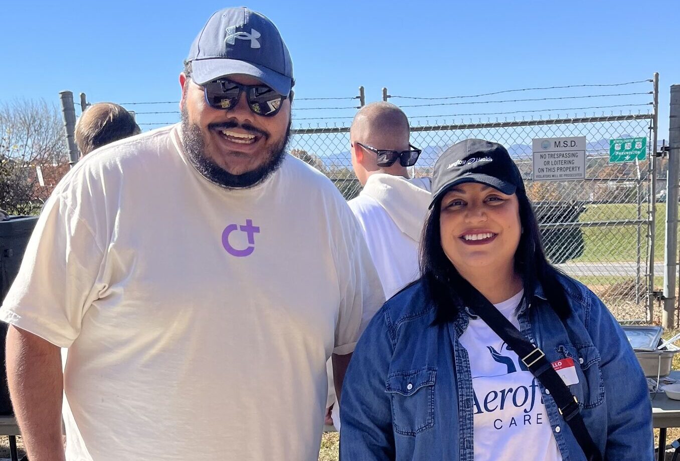 Two volunteers posing outdoors in branded shirts