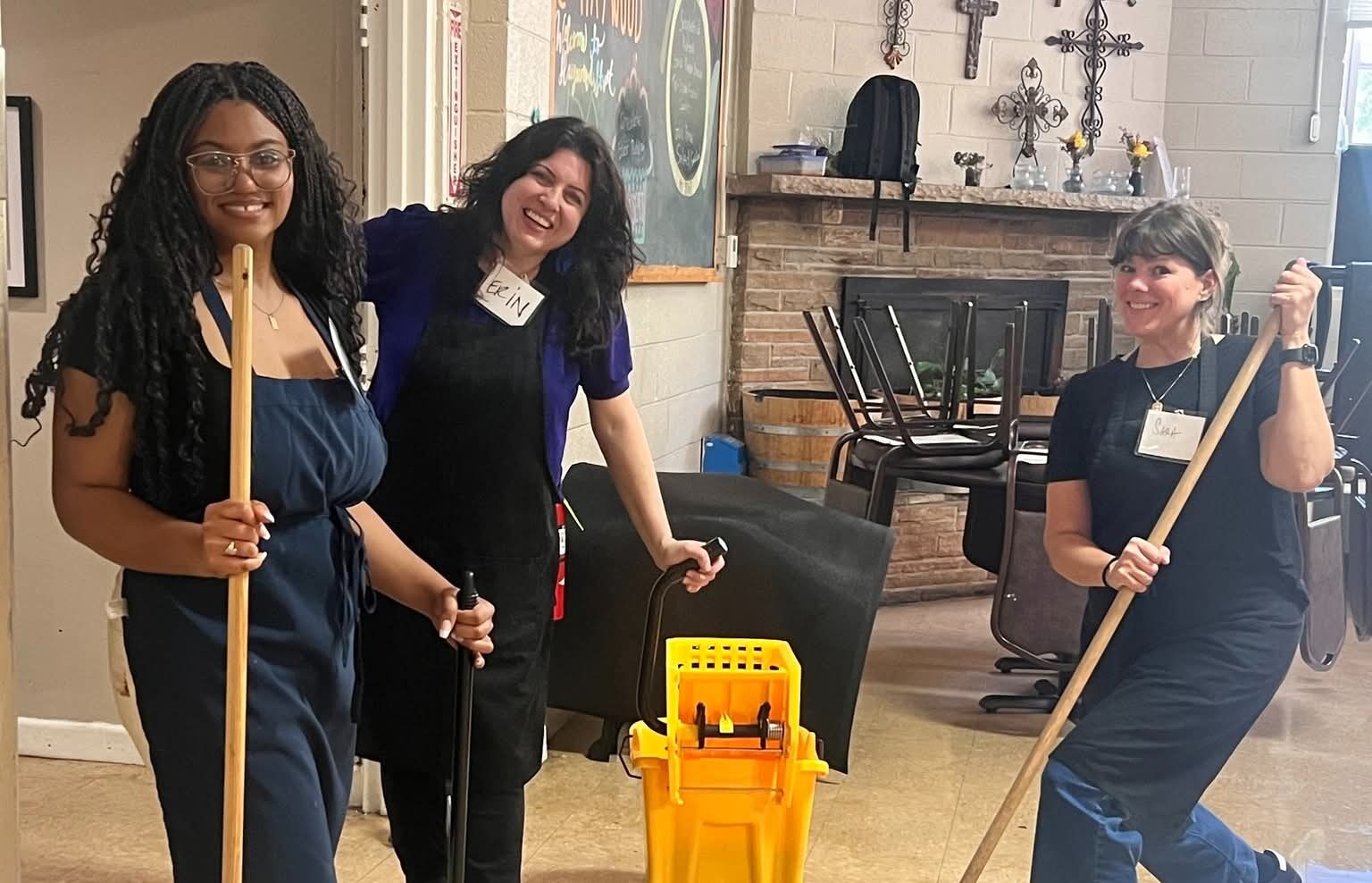 Three people cleaning indoors with mop